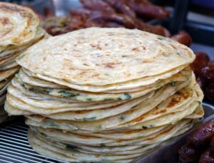 Scallion Pancakes stacked on a street food cart in Shanghai, China